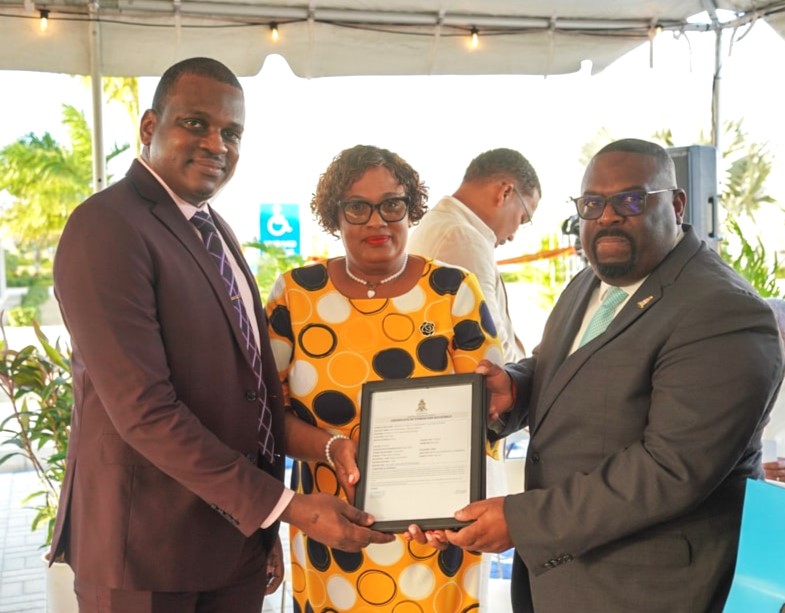 Director for Poinciana Rehabilitation Centre, Marcia Mullings-Thompson (centre) is presented with the Certificate of Occupancy for Poinciana Rehabilitation Centre.