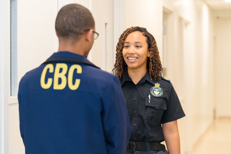 Two Cayman Islands Customs and Border Control Officers greeting each other.